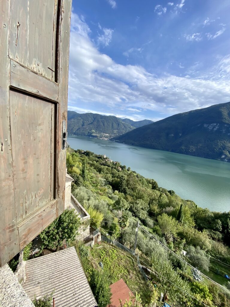 Scorcio sul Lago Ceresio dal borgo di Castello Valsolda, con un antico portone in primo piano
